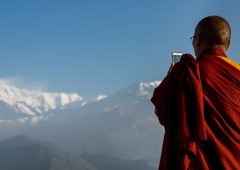Pokhara, Kaski District, Nepal - April 4, 2015: Buddhist monk with a mobile phone taking pictures of Annapurna range, Phokara, Nepal