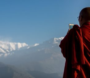 Pokhara, Kaski District, Nepal - April 4, 2015: Buddhist monk with a mobile phone taking pictures of Annapurna range, Phokara, Nepal